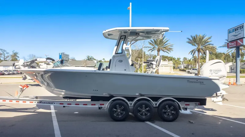 Slide: The Image of 2025 Tidewater 2500 Carolina Bay boat on trailer, parked outdoors under clear blue sky. - 4
