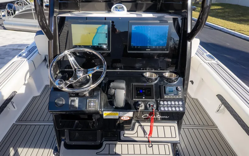 Slide: The Image of 2025 Tidewater 2500 Carolina Bay boat dashboard with dual screens and steering wheel. - 19
