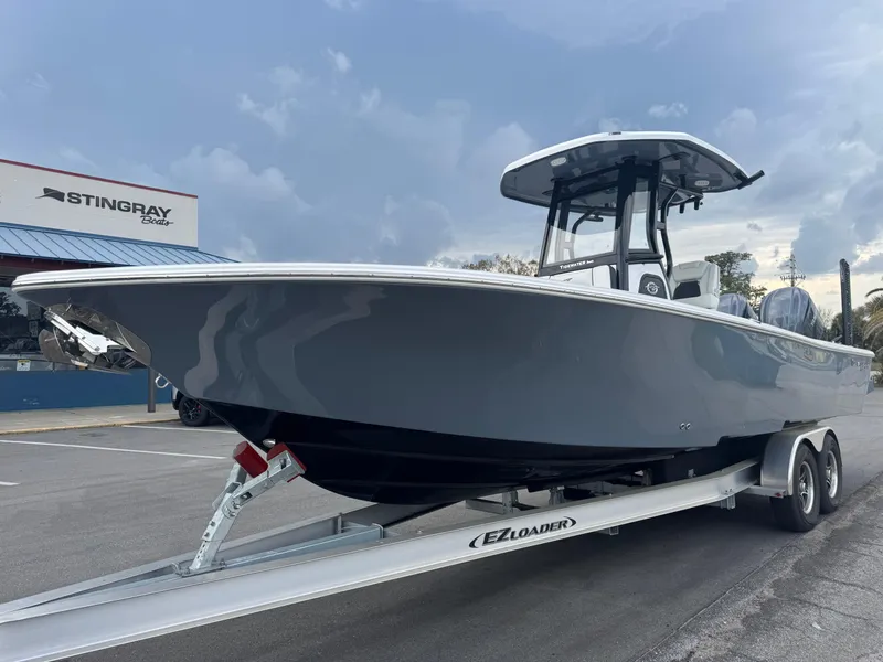 Slide: The Image of 2025 Tidewater 2700 Carolina Bay boat on trailer, parked near Stingray Boats building. - 6