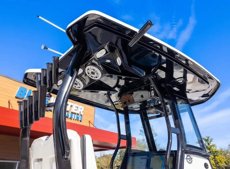 Slide: The Image of 2025 Tidewater 282CC boat with sleek black T-top and rod holders, under clear blue sky. - 11