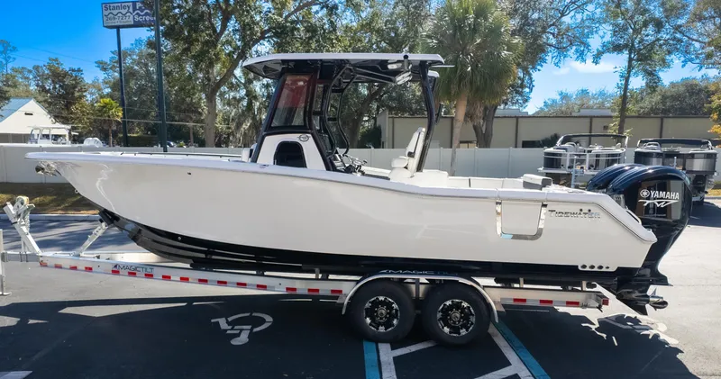 Slide: The Image of 2025 Tidewater 282CC boat on trailer, parked outdoors with trees in background. - 5