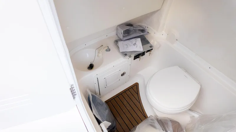 Slide: The Image of 2025 Tidewater 282CC boat interior with sink, toilet, and wooden floor mat. - 26