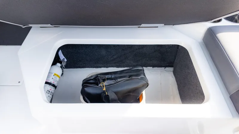 Slide: The Image of Storage compartment in 2024 Cobalt CS23 Surf boat with a bag and fire extinguisher. - 22