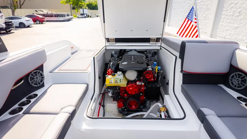 Slide: The Image of 2024 Cobalt CS23 Surf boat engine compartment with seating and American flag. - 26