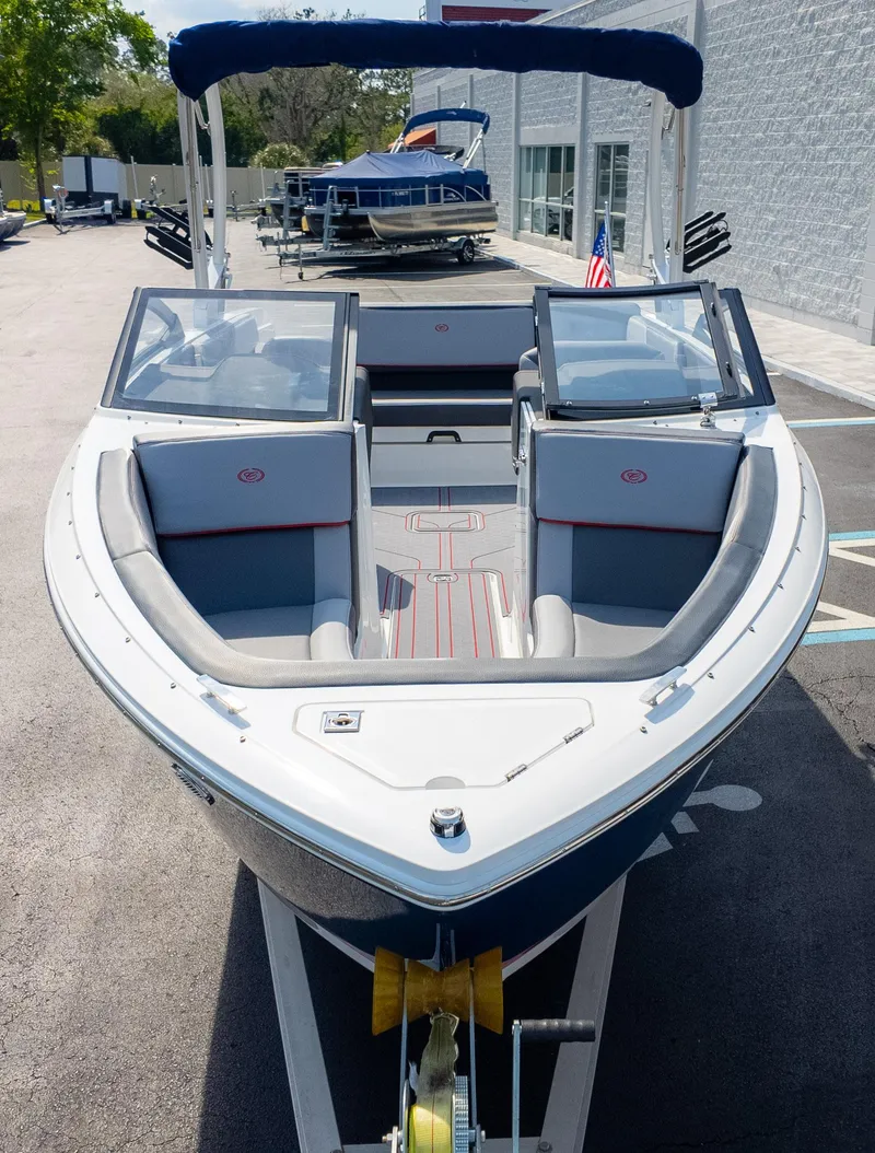 Slide: The Image of 2024 Cobalt CS23 Surf boat with open bow seating, parked outdoors. - 3