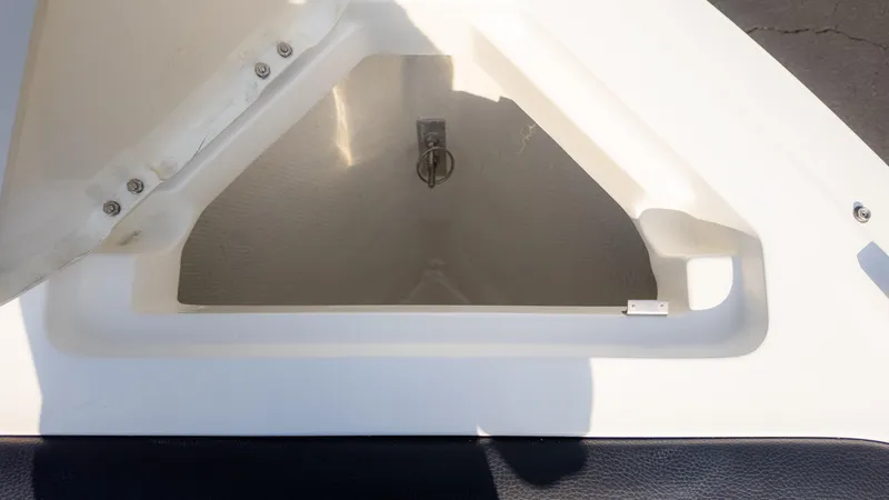 Slide: The Image of 2024 Cobalt CS23 Surf boat storage compartment, open lid, white interior. - 34