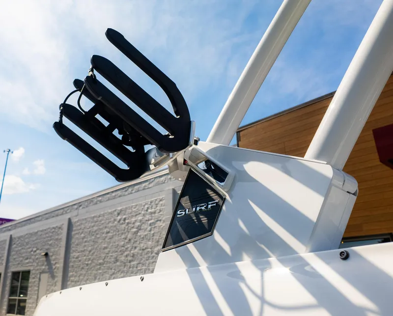 Slide: The Image of 2024 Cobalt CS23 Surf boat detail with wakeboard rack under clear sky. - 9