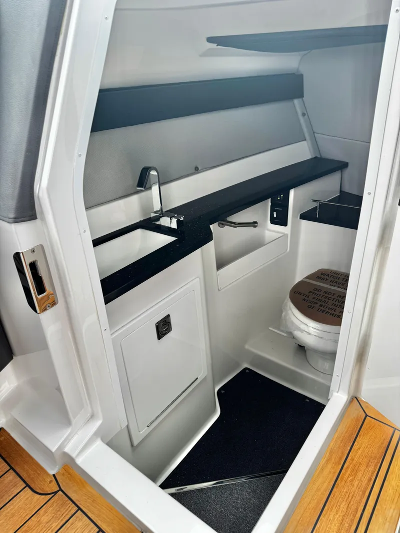 Slide: The Image of 2025 Cobalt R33 boat interior with compact bathroom, featuring a sink and toilet. - 19