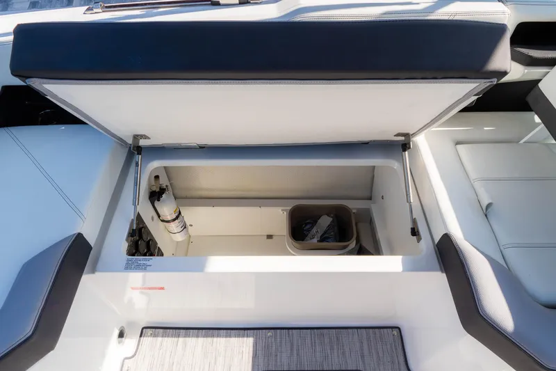 Slide: The Image of 2024 Cobalt R6 OB boat storage compartment with fire extinguisher and trash bin. - 28