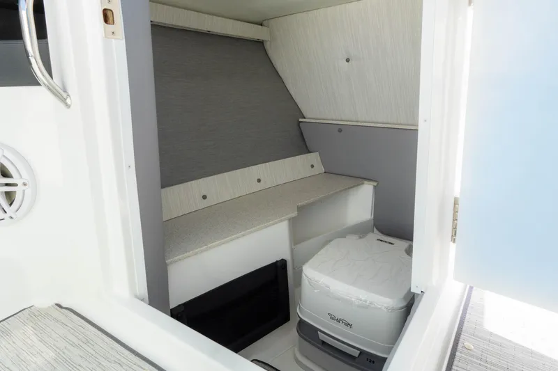 Slide: The Image of 2024 Cobalt R6 OB boat interior with compact toilet and storage area. - 37
