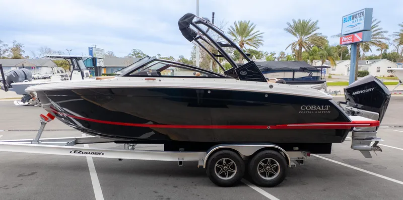 Slide: The Image of 2025 Cobalt R6OB boat on trailer at marina, featuring sleek black design and Mercury outboard engine. - 4