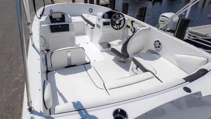 Slide: The Image of 2025 Stingray 172SC boat interior with white seating and steering wheel, docked by water. - 4