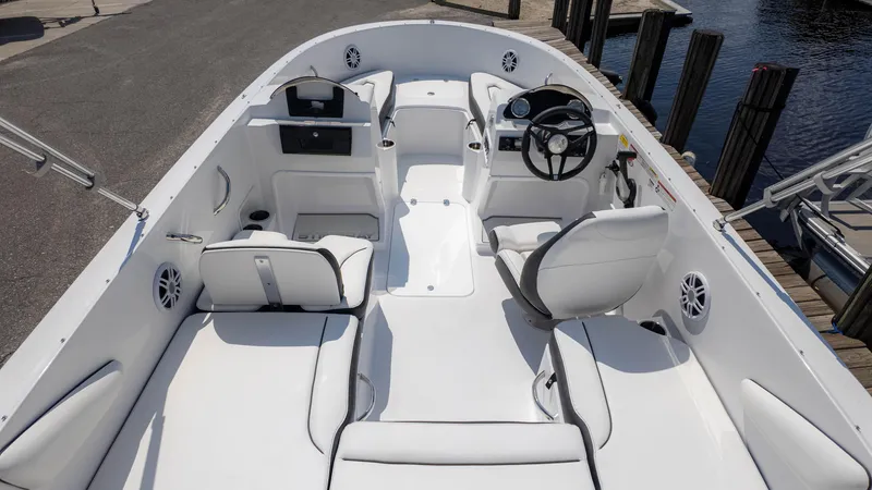 Slide: The Image of 2025 Stingray 172SC boat interior with white seating and steering console, docked by the water. - 7