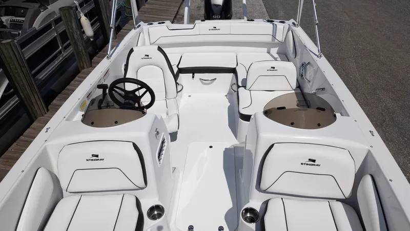 Slide: The Image of 2025 Stingray 172SC boat interior with white seating and steering wheel, docked at marina. - 9