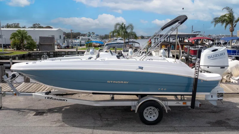 Slide: The Image of 2025 Stingray 192SC boat on trailer, docked at marina with Suzuki engine. - 1