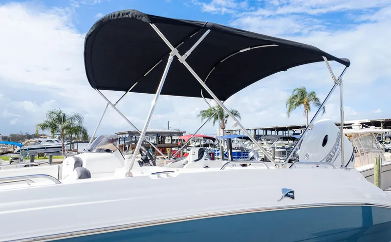 Slide: The Image of 2025 Stingray 192SC boat with canopy, docked at marina under blue sky. - 30