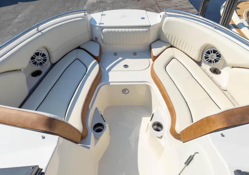 Slide: The Image of 2024 Stingray 211DC boat interior with beige and brown seating, cup holders, and speakers. - 11