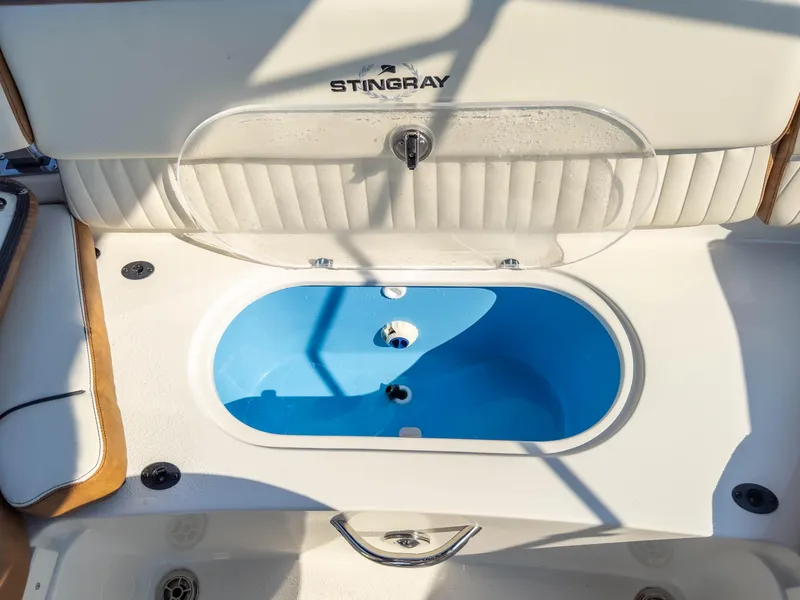 Slide: The Image of 2024 Stingray 211DC boat interior with open storage compartment and blue interior. - 19