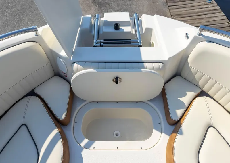 Slide: The Image of 2024 Stingray 211DC boat interior with cushioned seating and storage compartment. - 24