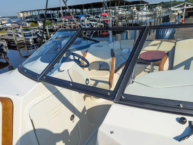 Slide: The Image of 2024 Stingray 211DC boat interior with seating and steering wheel at marina. - 27