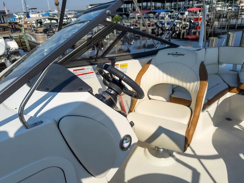 Slide: The Image of 2024 Stingray 211DC boat interior with steering wheel and seating at marina. - 29