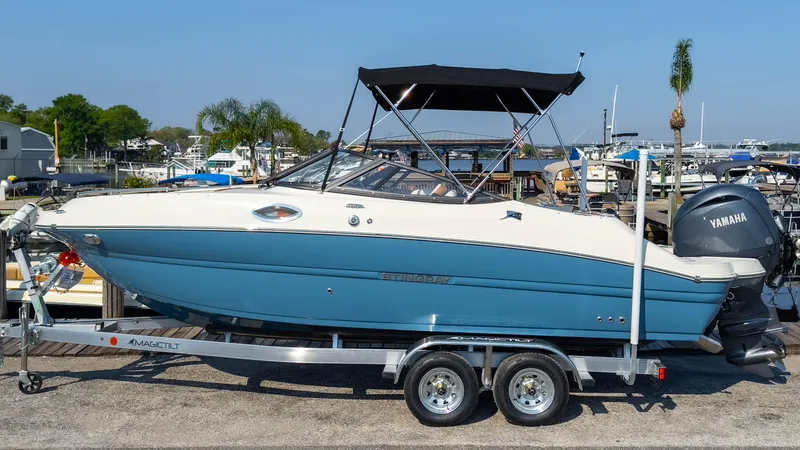 Slide: The Image of 2024 Stingray 211DC boat on trailer, docked at marina with Yamaha engine. - 3