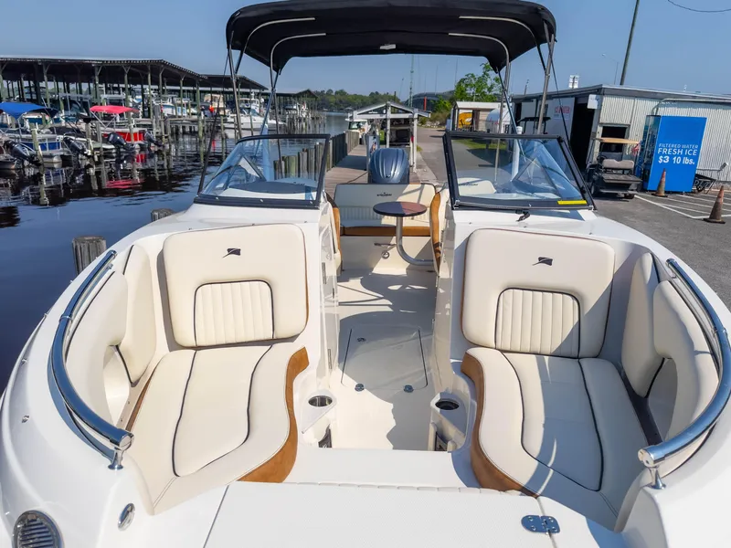 Slide: The Image of 2024 Stingray 211DC boat interior with plush seating at a marina dock. - 36