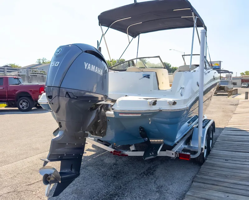 Slide: The Image of 2024 Stingray 211DC boat with Yamaha 150 engine on trailer, parked outdoors. - 38