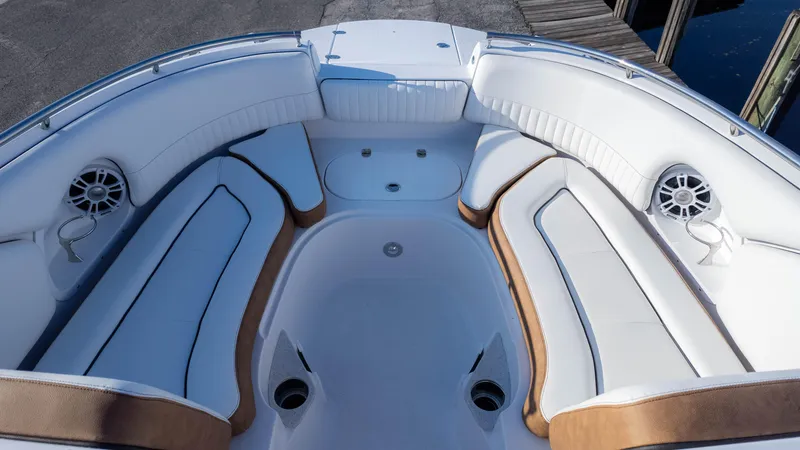 Slide: The Image of 2025 Stingray 231DC boat interior with white and tan seating, featuring speakers and cup holders. - 12