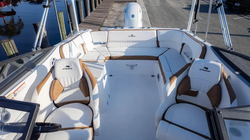 Slide: The Image of 2025 Stingray 231DC boat interior with white and brown seating, docked by the water. - 14