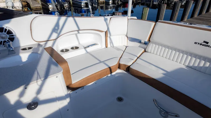 Slide: The Image of 2025 Stingray 231DC boat interior with white and brown seating, cup holders, and speaker. - 18
