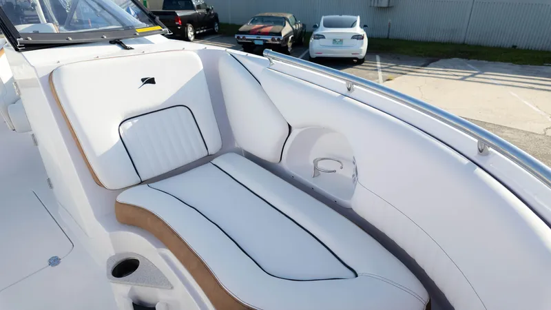 Slide: The Image of 2025 Stingray 231DC boat interior with white and tan seating in a parking lot. - 22