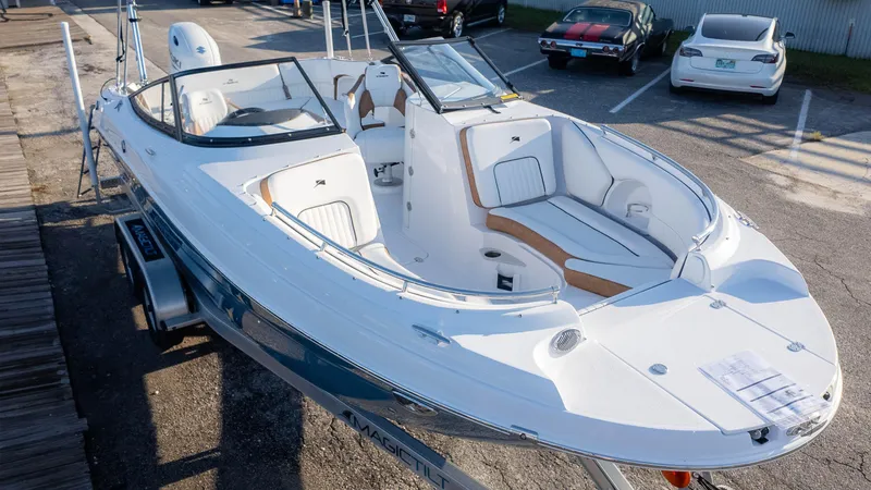 Slide: The Image of 2025 Stingray 231DC boat with sleek design, parked on a trailer in a lot. - 3