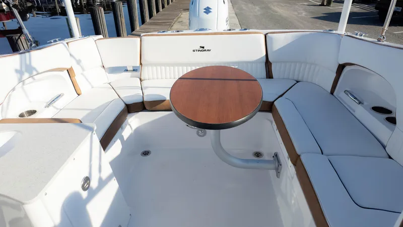 Slide: The Image of 2025 Stingray 231DC boat interior with white seating and wooden table. - 30