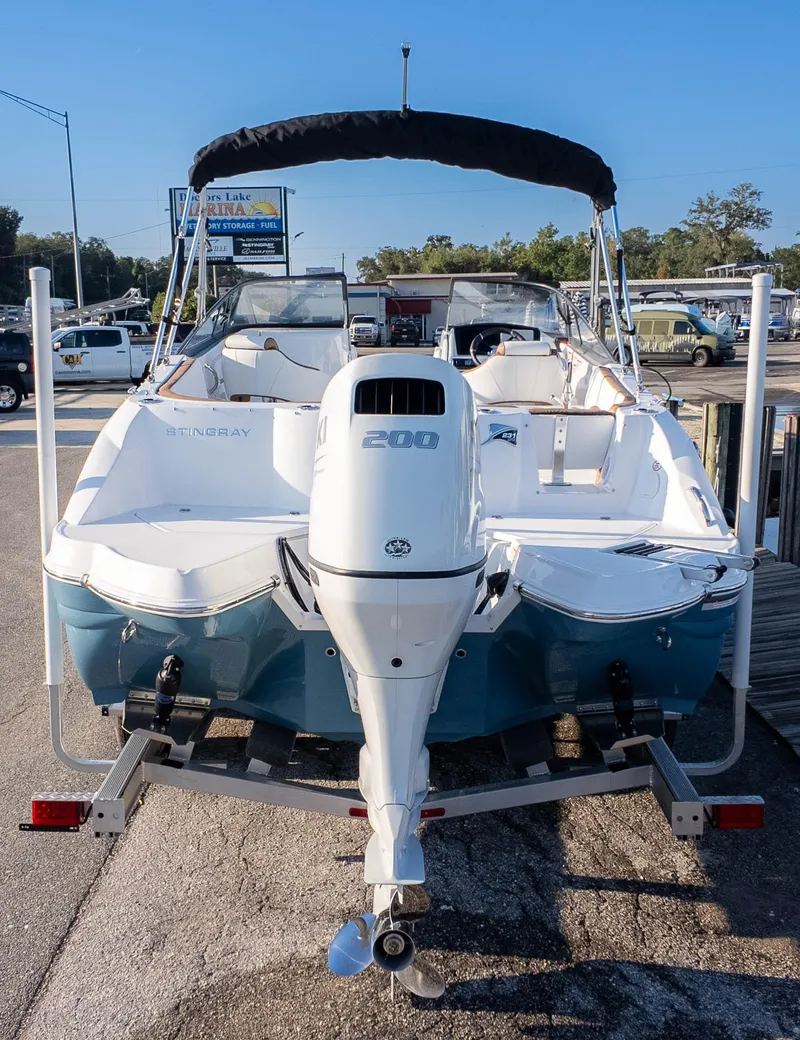 Slide: The Image of 2025 Stingray 231DC boat with outboard motor on trailer, parked at marina. - 4