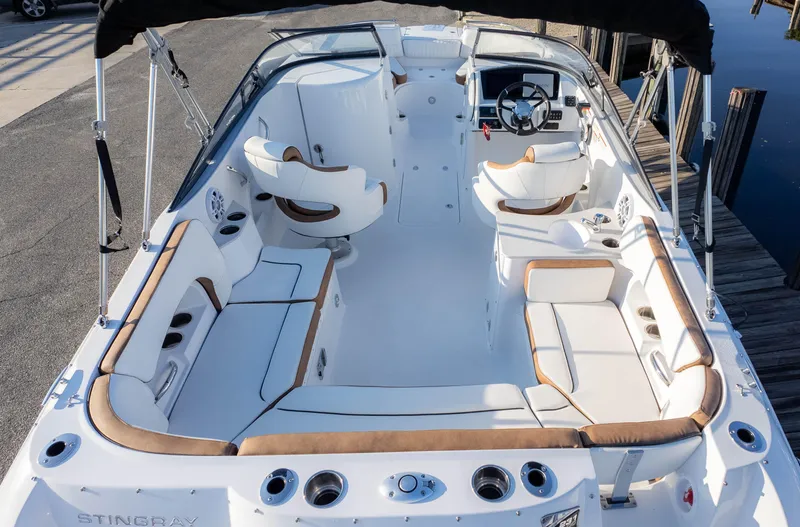 Slide: The Image of 2025 Stingray 231DC boat interior with white and tan seating, docked by the water. - 7
