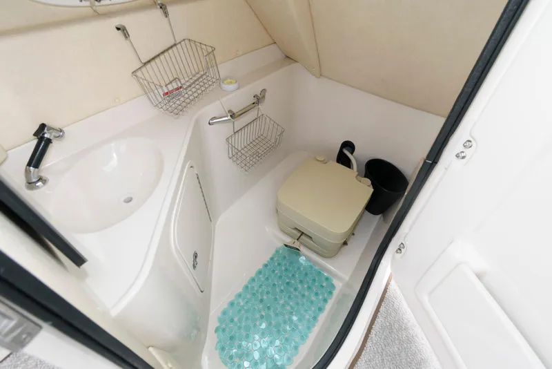 Slide: The Image of 2008 Sea Ray 260 Sundeck bathroom with sink, portable toilet, and storage baskets. - 9