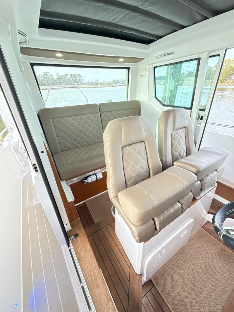 Slide: The Image of 2019 Axopar 28 CABIN interior with beige seating and wood flooring. - 11