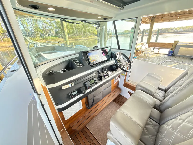 Slide: The Image of 2019 Axopar 28 CABIN interior with steering wheel and navigation system. - 13