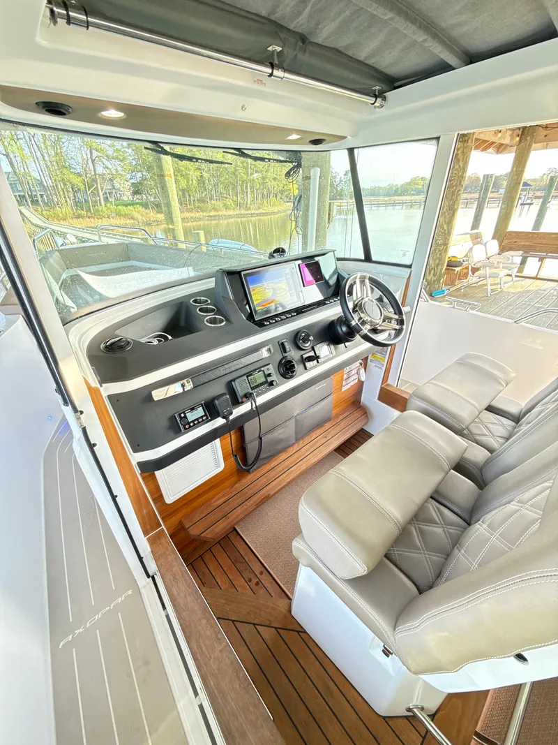 Slide: The Image of 2019 Axopar 28 CABIN interior with modern helm, leather seats, and navigation system. - 18