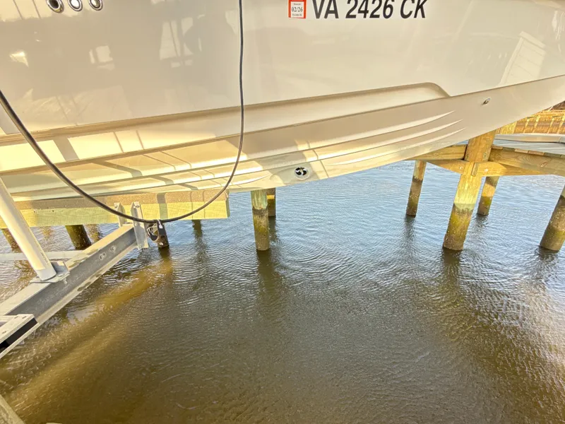 Slide: The Image of 2019 Axopar 28 CABIN boat on lift above water, showing hull and registration. - 29