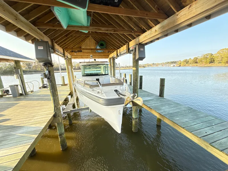 Slide: The Image of 2019 Axopar 28 CABIN boat docked under wooden shelter on a serene lake. - 3