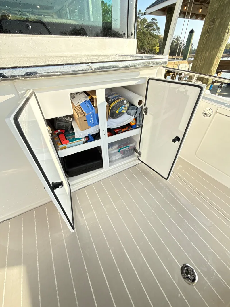 Slide: The Image of 2019 Axopar 28 CABIN storage compartment with open doors, revealing organized boating supplies. - 30