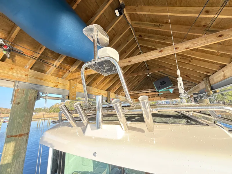 Slide: The Image of 2019 Axopar 28 CABIN boat under wooden dock roof, featuring rod holders and equipment. - 44