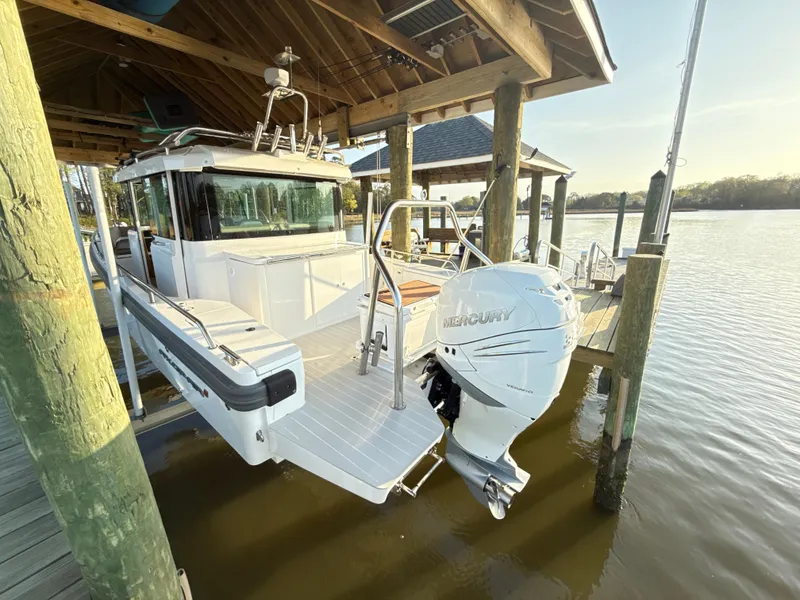Slide: The Image of 2019 Axopar 28 CABIN boat docked under a wooden shelter with Mercury outboard engine. - 5