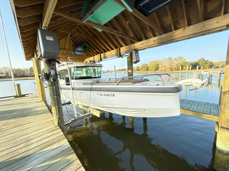 Slide: The Image of 2019 Axopar 28 CABIN boat docked under a wooden shelter by the water. - 6