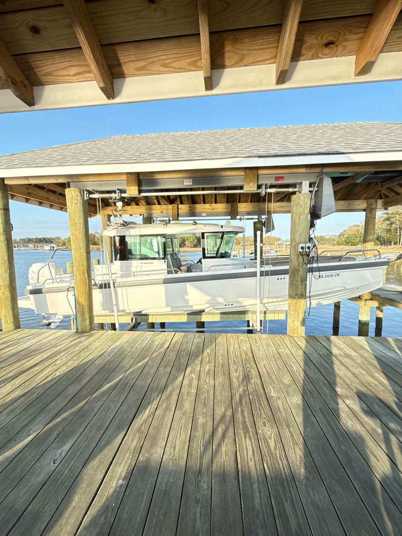 Slide: The Image of 2019 Axopar 28 CABIN boat docked under wooden shelter on a sunny day. - 8