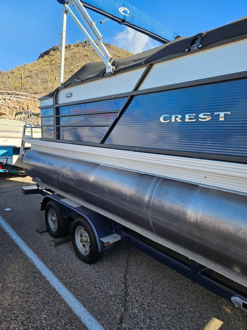 Slide: The Image of 2018 Crest 200 CA pontoon boat on trailer, parked near desert landscape. - 2
