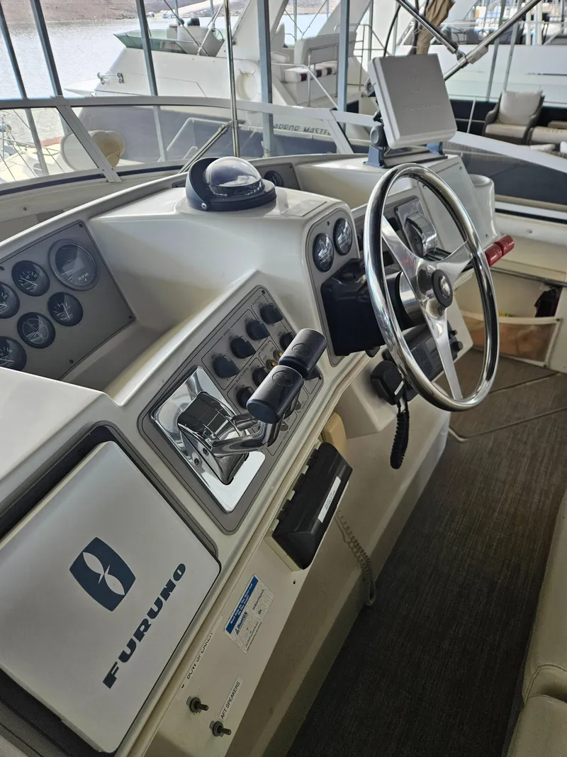 Slide: The Image of 1997 Carver 455 Aft Cabin Motoryacht helm with steering wheel and navigation controls. - 18