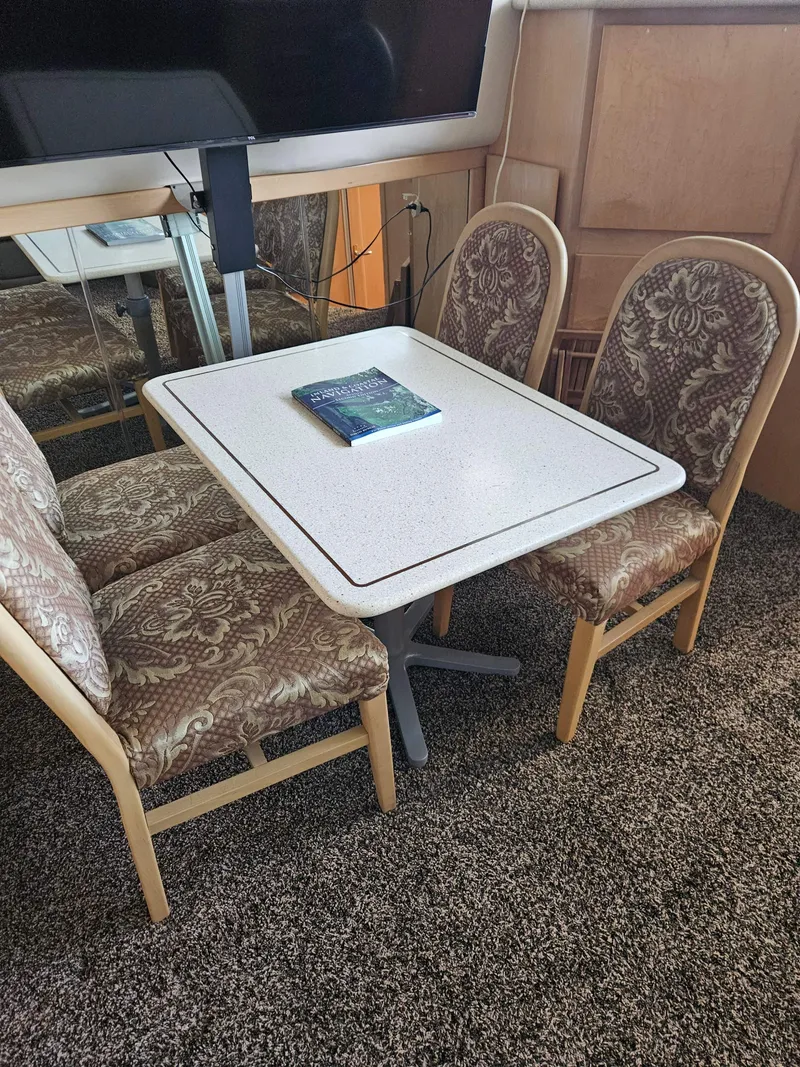 Slide: The Image of Dining area in 1997 Carver 455 Aft Cabin Motoryacht with patterned chairs and table. - 24